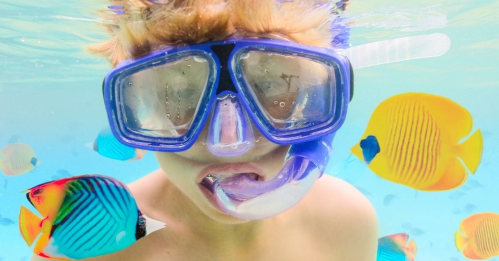niño haciendo snorkel y usando camara de fotos acuatica 